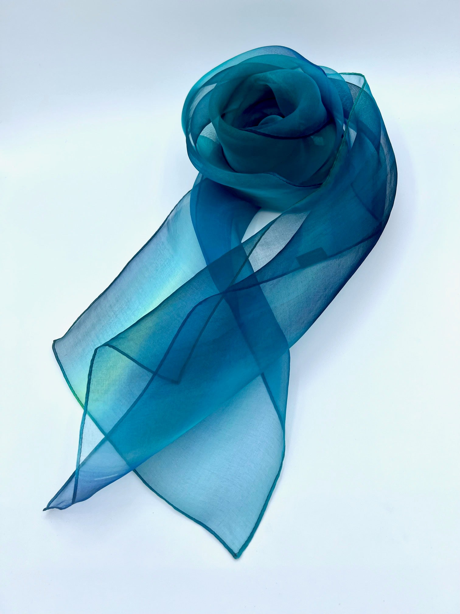 Experience the perfect harmony of art and elegance with our one-of-a-kind silk scarf—a designer accessory that transcends fashion into a realm of beauty and inspiration. Handcrafted with meticulous care, each piece is hand-dyed to create a stunning interplay of multicolor tones, forming a vibrant rainbow of hues that shimmer with soft transparency. Designed to complement any outfit, from casual wear to formal dresses, this versatile scarf enhances your personal style with a touch of uniqueness. Whether worn